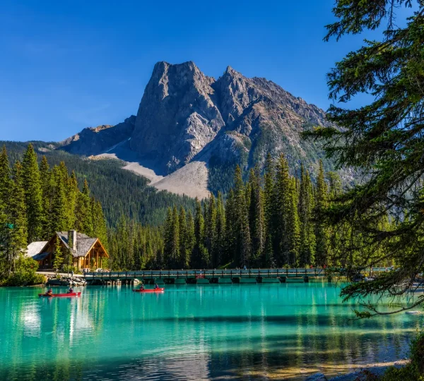 Emerald Lake scenic view with turquoise water, pine forest, mountain lodge, bridge, and Canadian Rockies landscape
