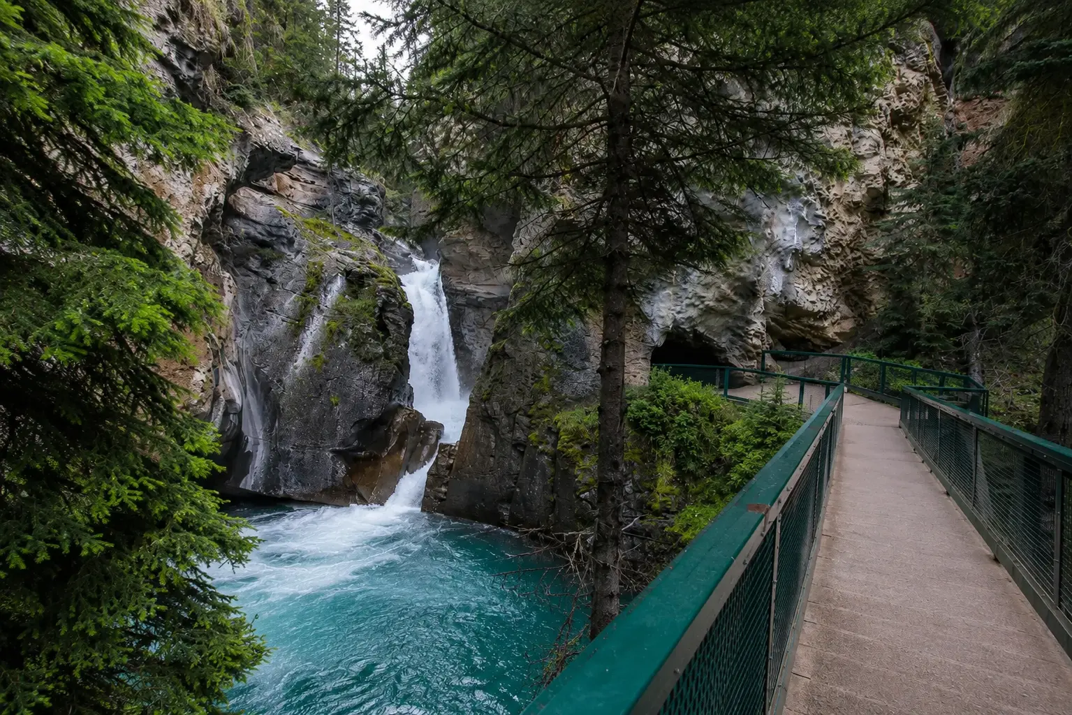 Johnston Canyon waterfall with turquoise water, forest walkway, rocky cliffs, and natural Canadian Rockies scenery
